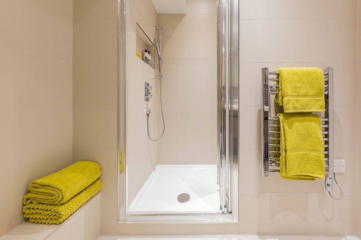 Verve Properties West London flat relaxing shower room with neutral wall tiles and bright yellow towels from John Lewis