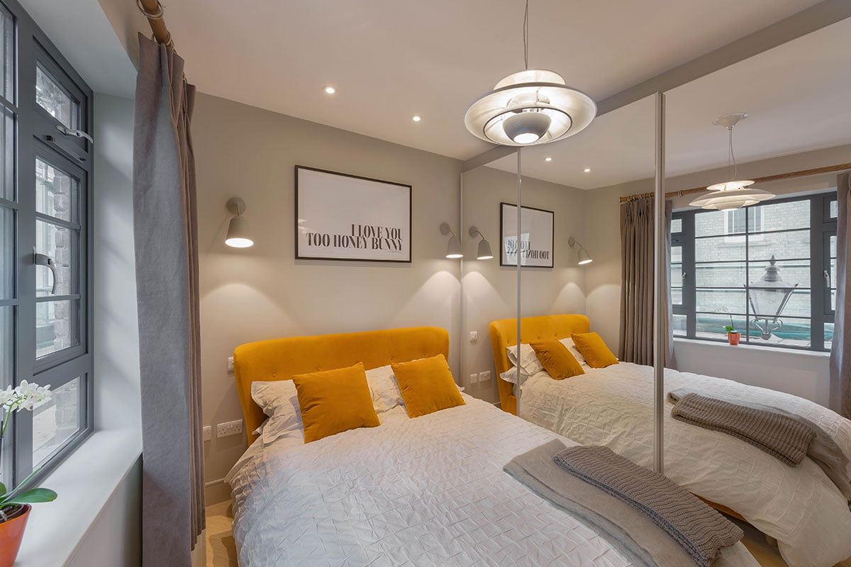 interior design of bedroom for Brenford flat by Element Studios with mirrored wardrobes and Smoke burnt orange bed from Loaf