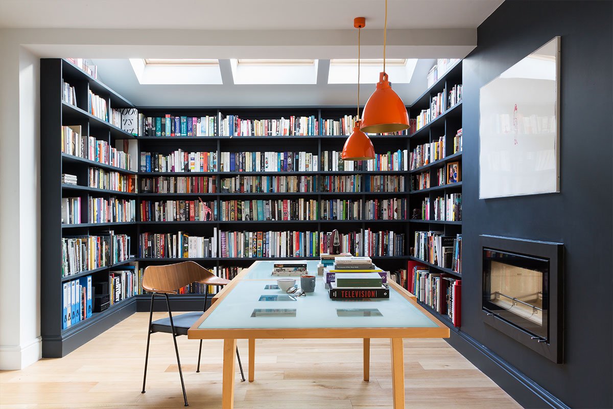 central fireplace dividing bespoke library with mid-century desk and chair orange Jielde pendants from Holloways of Ludlow