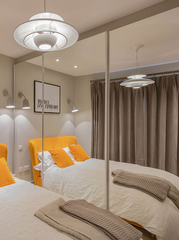 pop of colour cosy modern bedroom interior with Jonah dandelion yellow double bed from Made and whole wall mirrored wardrobes