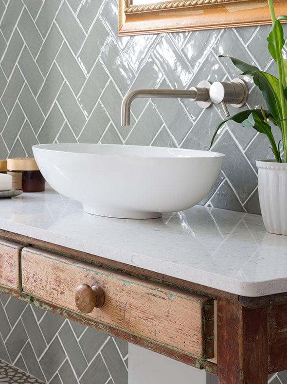 wall mounted brushed steel taps over stone basin and worktop with vintage desk as wash stand from Oxford interior designers