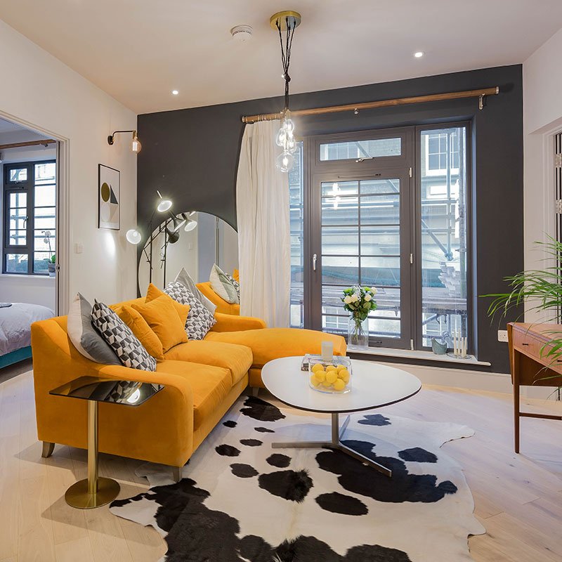 Brentford flat interior by Element Studios with Loaf Oscar burnt orange sofa, cowhide rug and Tom Dixon Flash side table