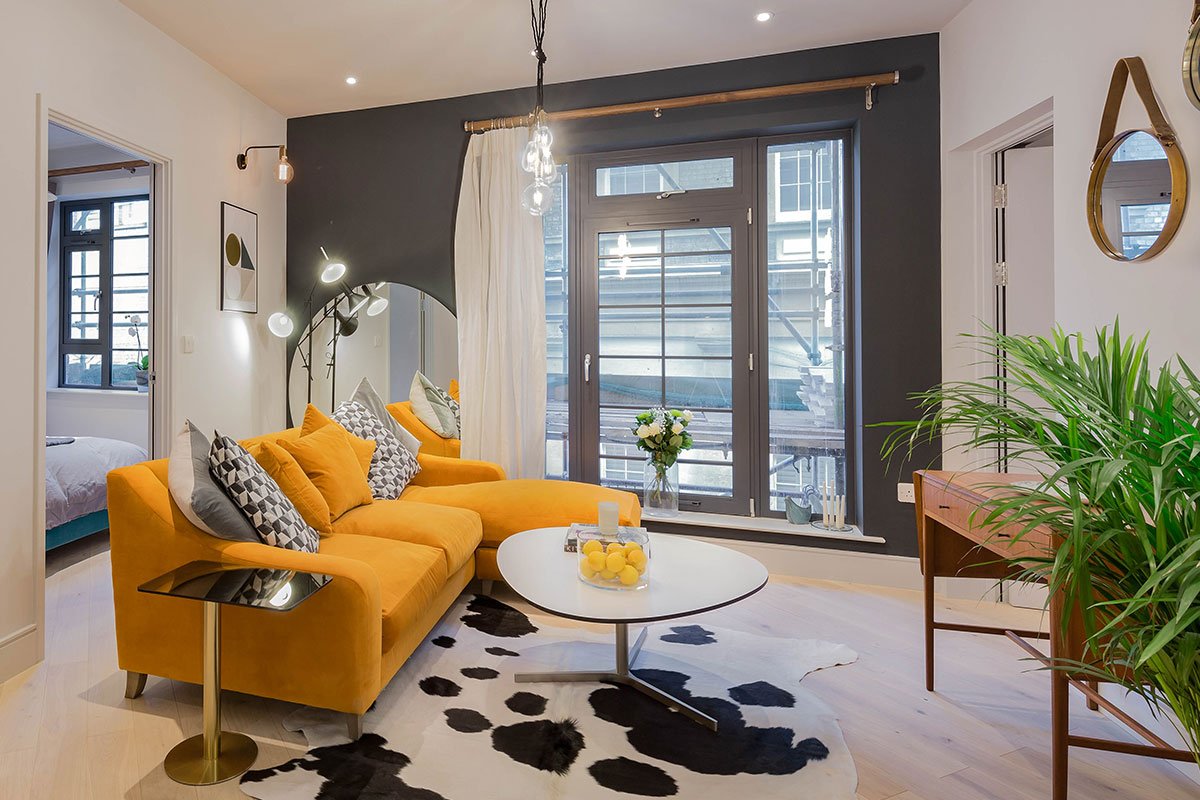 Brentford flat Tom Dixon Flash side table cowhide rug Oscar velvet burnt orange sofa Junction wall lights Tom Pigeon prints
