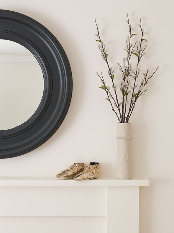 close-up of circular mirror in Railings and fireplace in School House White, Farrow & Ball paints with small ceramic vase