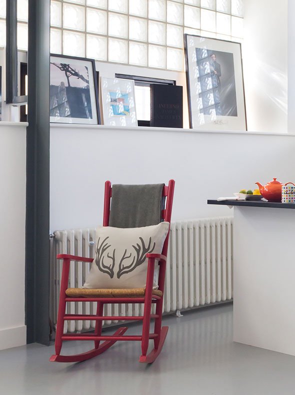 Ammunitions factory conversion East London kitchen with red rocking chair grey floor paint and dark slate kitchen worktop