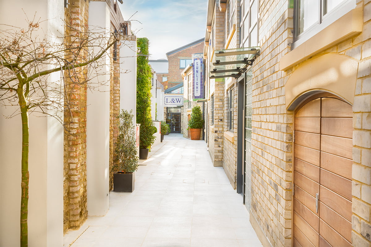 stone paved mews walkway to Loud and Western townhouse redevelopment with private entrances to houses in Fulham during autumn